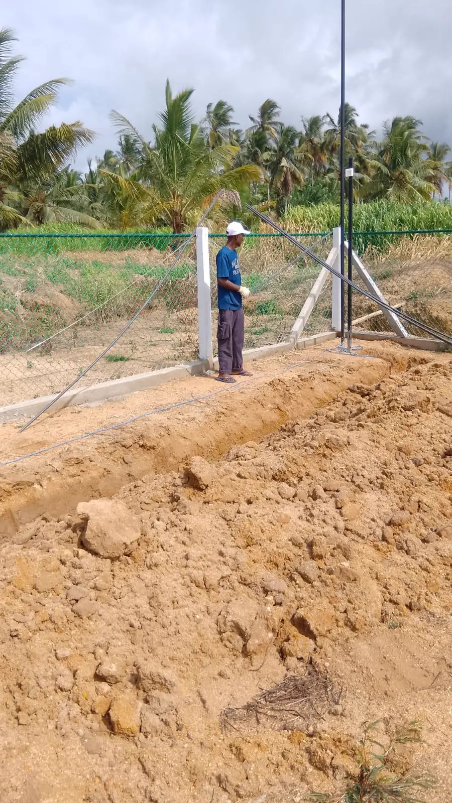 TKWIT technician working on outdoor site infrastructure beside perimeter fencing in Sri Lanka